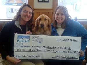 Shannon Camara, Manager of Communications at Concord-Merrimack County SPCA, receives a check for $3,935 from Lori Rowell, Director of Marketing at Pats Peak, and Roxy, the ski area's golden retriever mascot. (photo: Pats Peak)