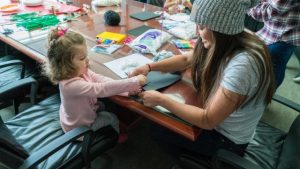 Aerials skier Kira Tanghe works on a cotton ball ghost Halloween craft with a patient. (photo: Primary Children's Hospital)